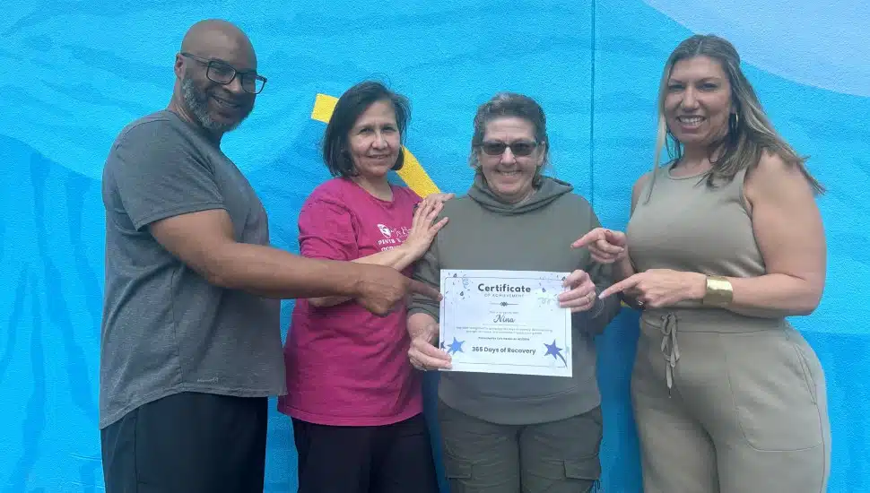 Nina holds a certificate recognizing a year in recovery, with the Safe Harbor staff who supported her.