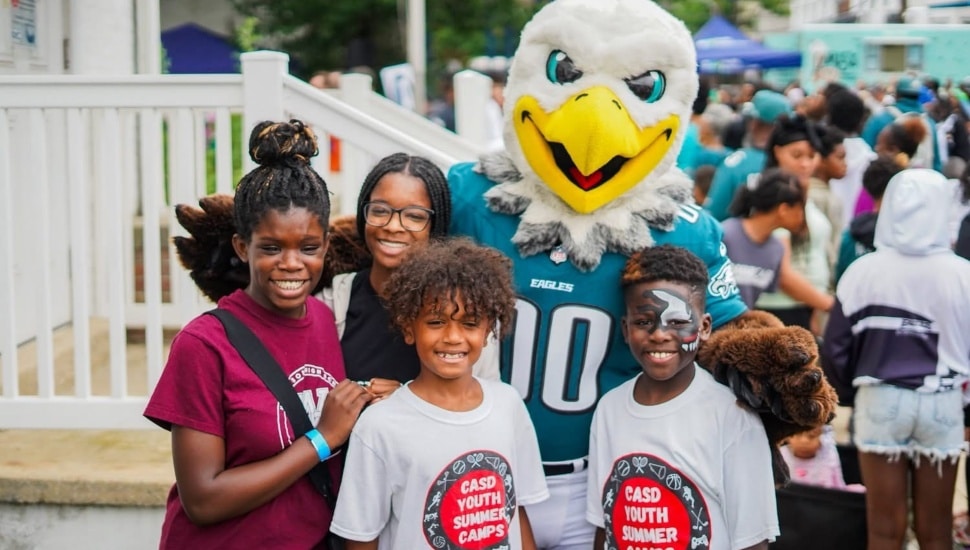 Children pose with the Philadelphia Eagles mascot Scoop at a Chester County OIC community block party.