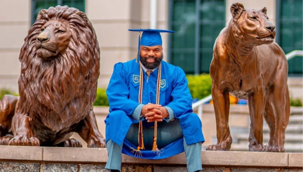 Delorean Andrews in cap and gown on the campus of Widener University.