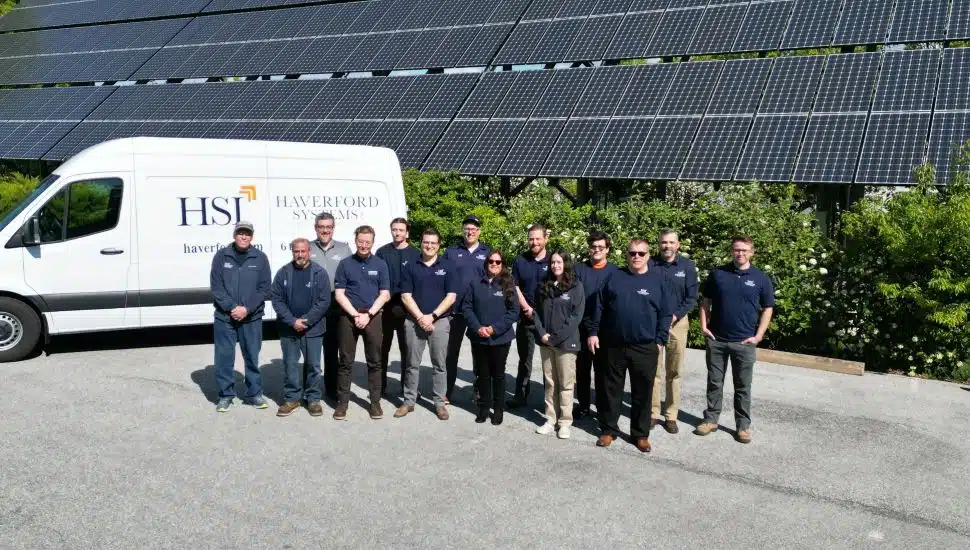 Haverford Systems team members outside with van near them and solar panels in background.