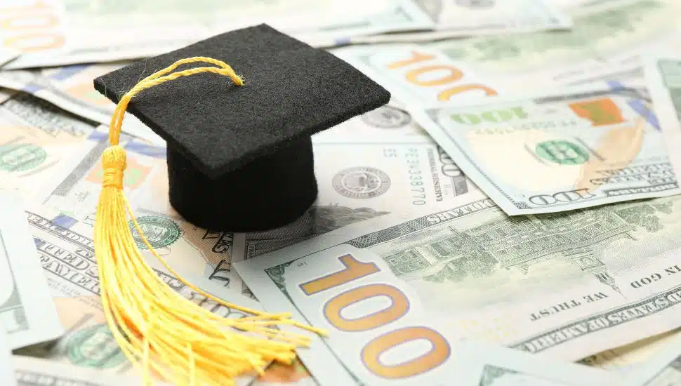 Tiny grad hat on top of spread of $100 bills.