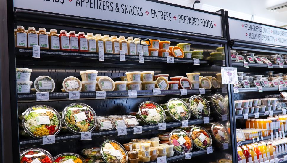 Rows of premade meals, drinks, and snacks on shelves at an ANEU Kitchens location.