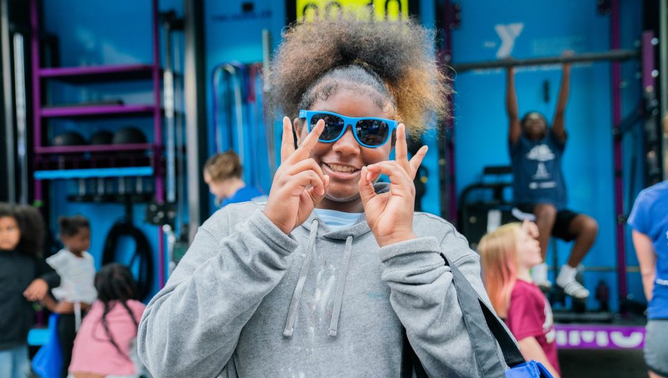 Girl at Block Party smiling at camera with blue sunglasses.