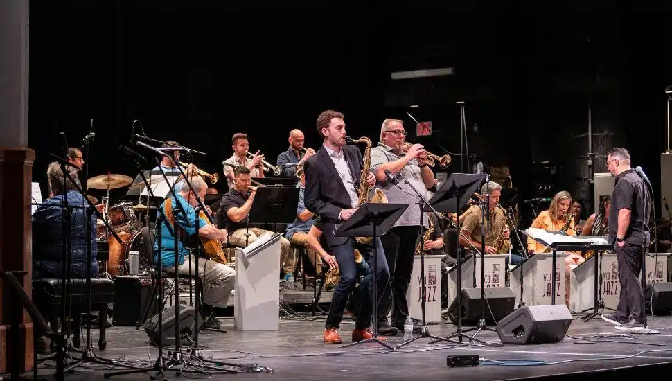 Alumni musicians perform on stage during the West Chester University Criterions Alumni Reunion Concert, featuring a full jazz ensemble with saxophones, trumpets, drums and piano in Emilie K. Asplundh Concert Hall.