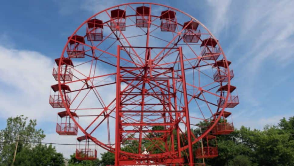 Red Phoenix Wheel with blue sky, clouds, and green trees in background.