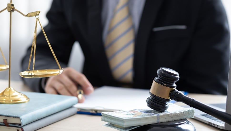 Bankruptcy concept with lawyer, justice scales, and gavel with money under it.