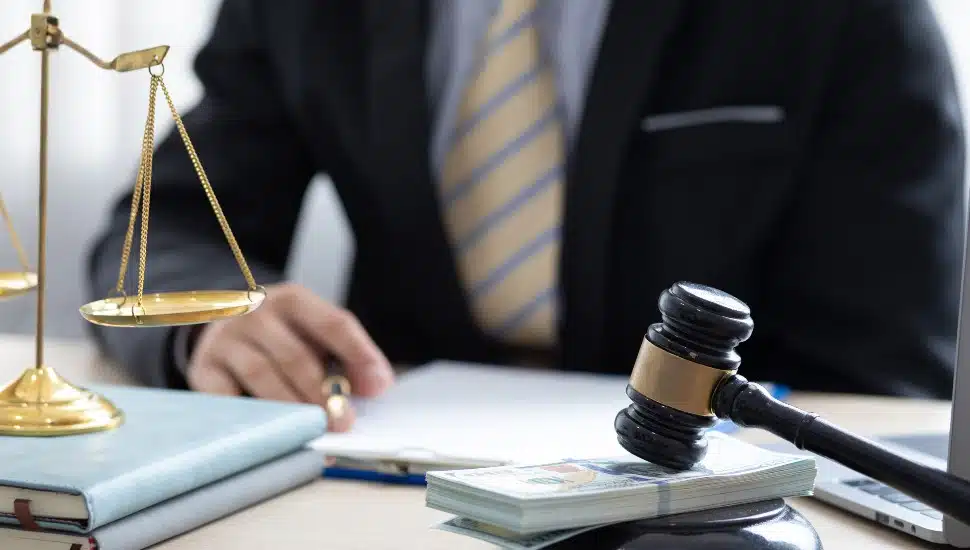 Bankruptcy concept with lawyer, justice scales, and gavel with money under it.